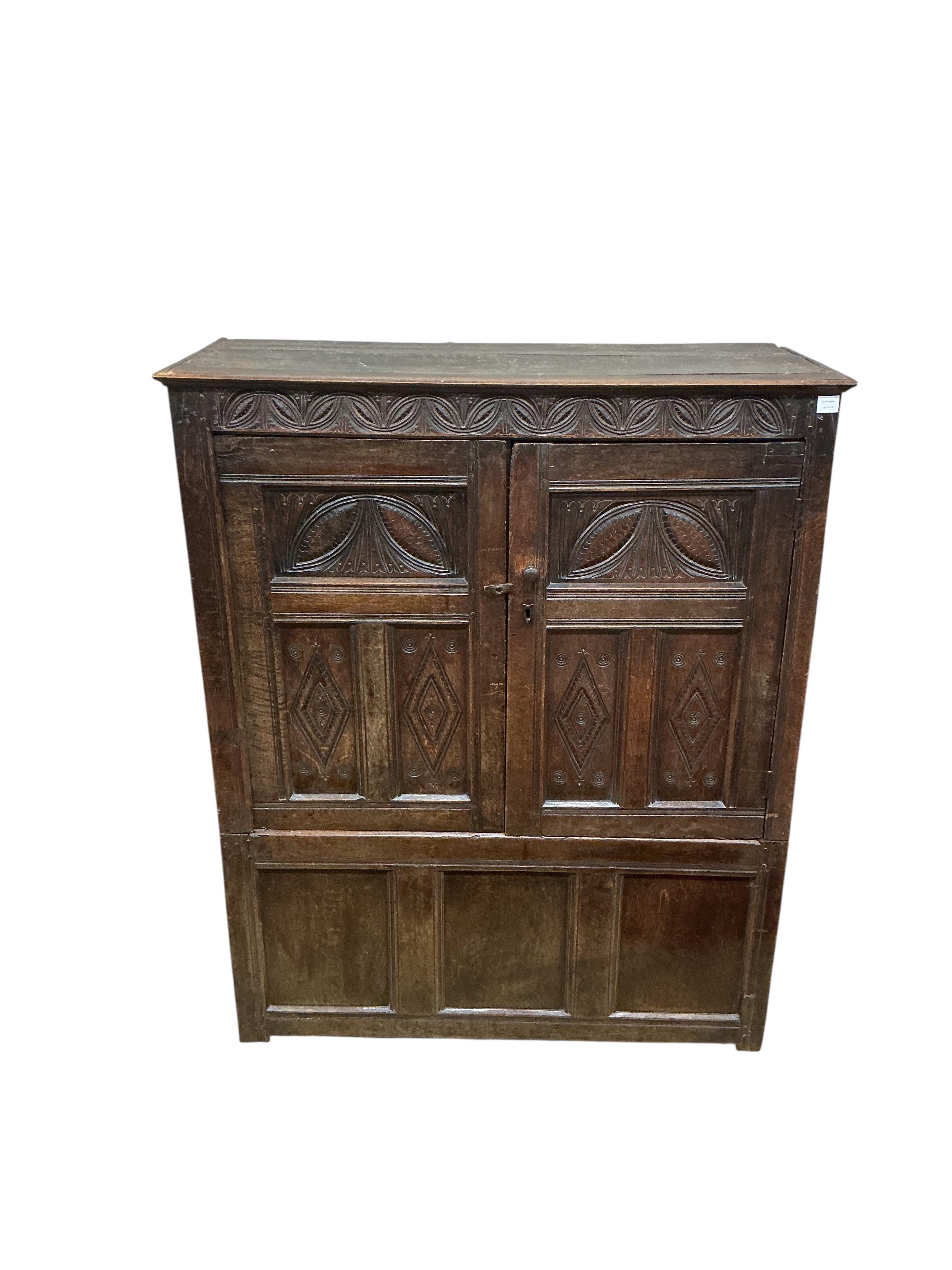 An early 18th century carved oak hanging cupboard, width 133cm, depth 56cm, height 162cm